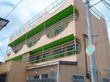大学に近い住宅街にある集合住宅型のホームである。暖色系の壁にベランダの緑色がデザイン性のある、モダンな外観である。