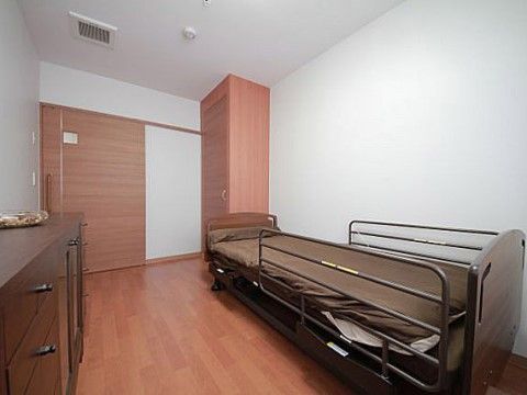 大きめの収納タンスと天井まで高さのあるクローゼット、ベッドが設置された部屋