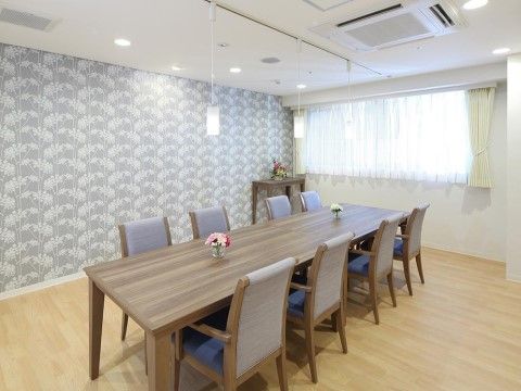 ８人掛けの長テーブルが置かれたシンプルな部屋。窓があり、日が差し込んで明るい。空調設備がついている。