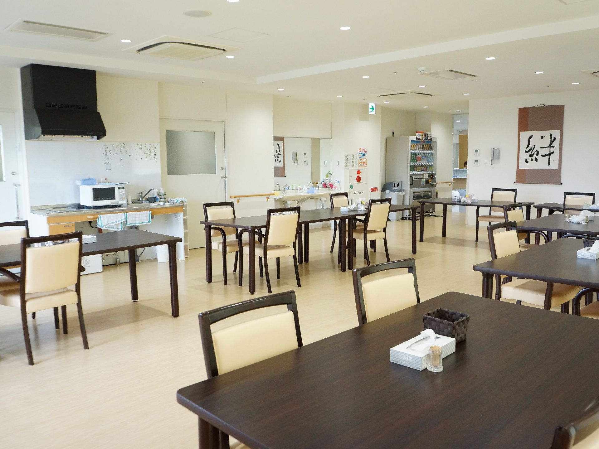 食堂は広々としている。茶色い長いテーブルの周りに白い椅子が並べられている。壁には絆と書かれた掛け軸がある。