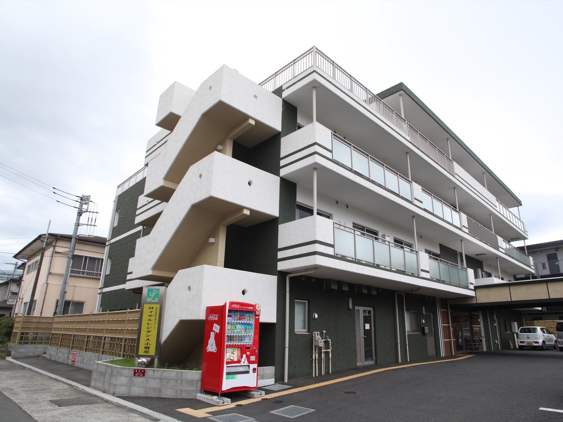 施設前の道路から見た時の施設全景。他に高い建物はなく、閑静な住宅街の中にある。道路に面して各階につながる非常階段がある。