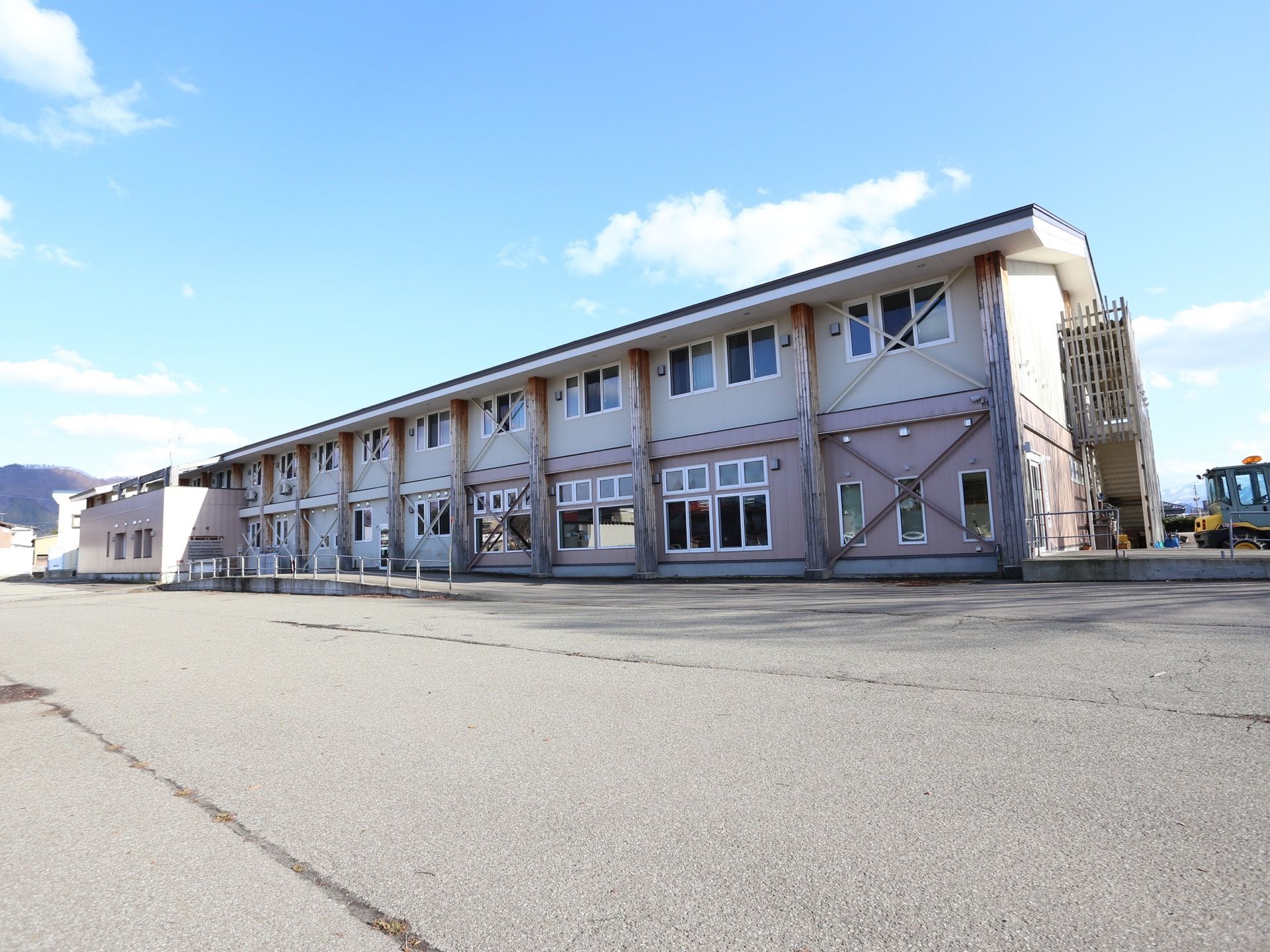 晴天の日にゆとりある敷地に立地する２階建ての施設である。周囲に高い建物がなく、非常階段やスロープを完備している。