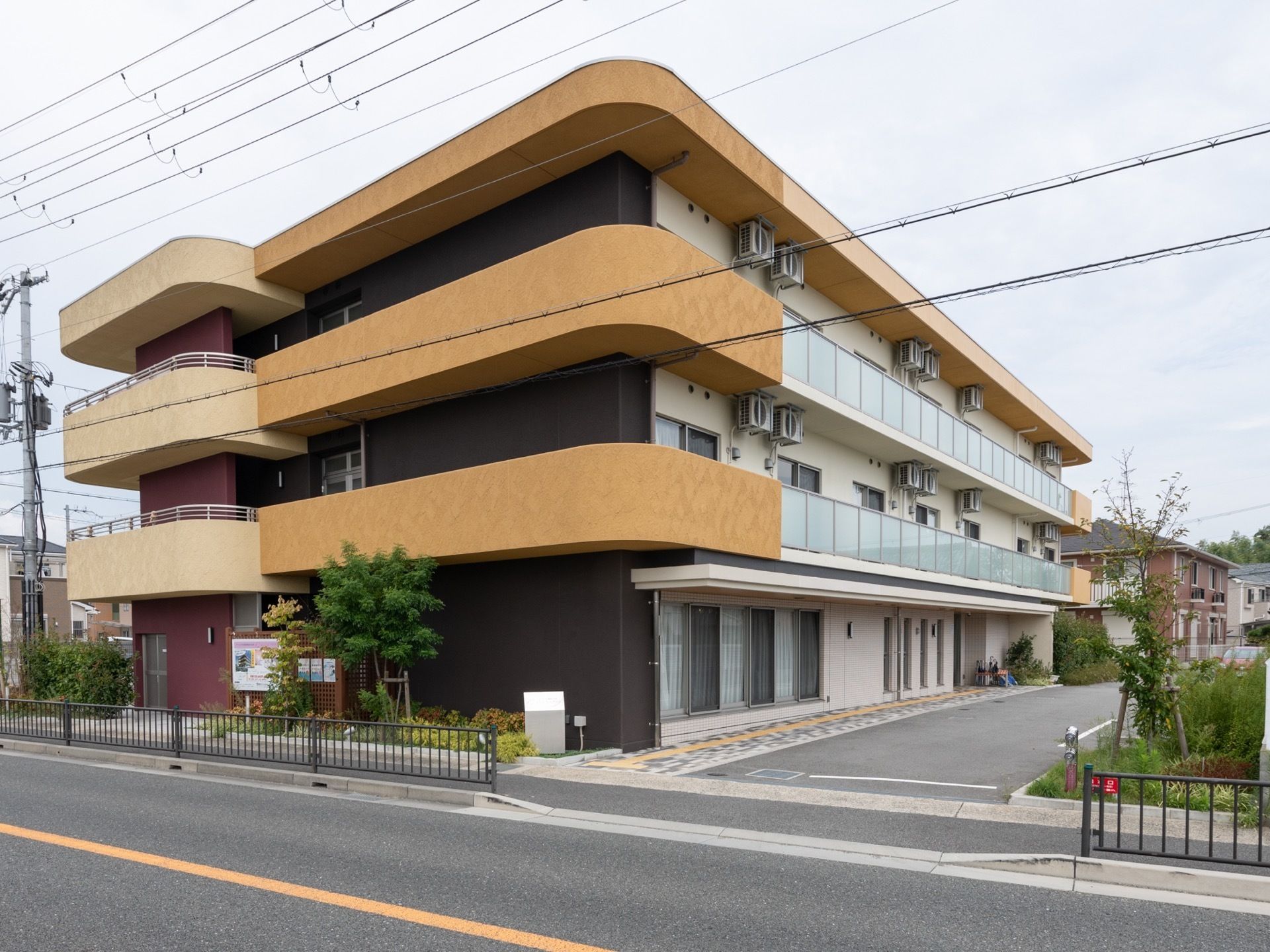 施設はバス通りに面しており、敷地内へ車で入ることができる。オレンジに塗られた屋根の角は丸く面取りがされている。