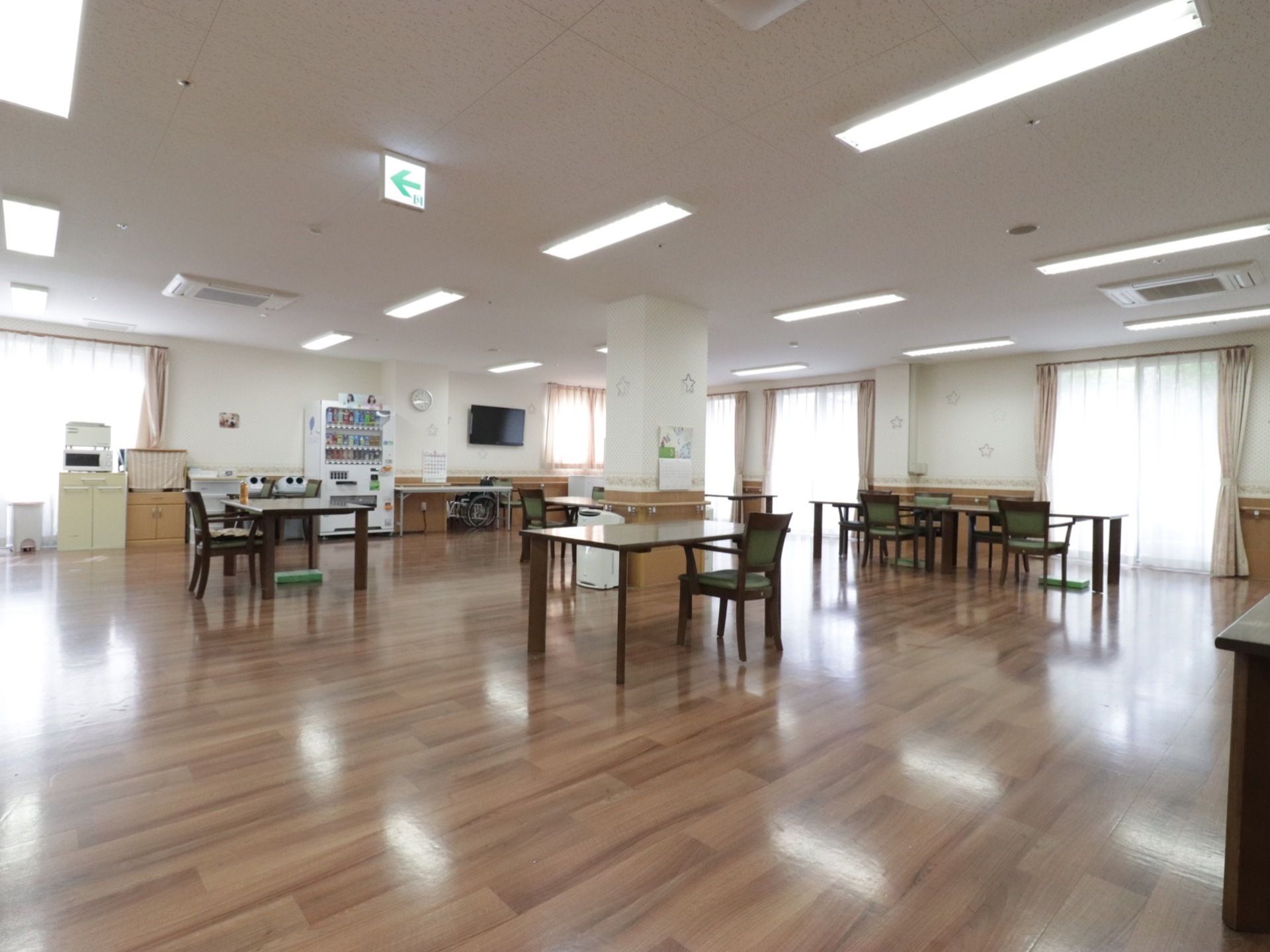 ガラス戸が複数設置された食堂は、開放的な空間にテーブルと椅子が幾つか配置されている。壁際には棚の上に電子レンジがあり自動販売機も置いてある。