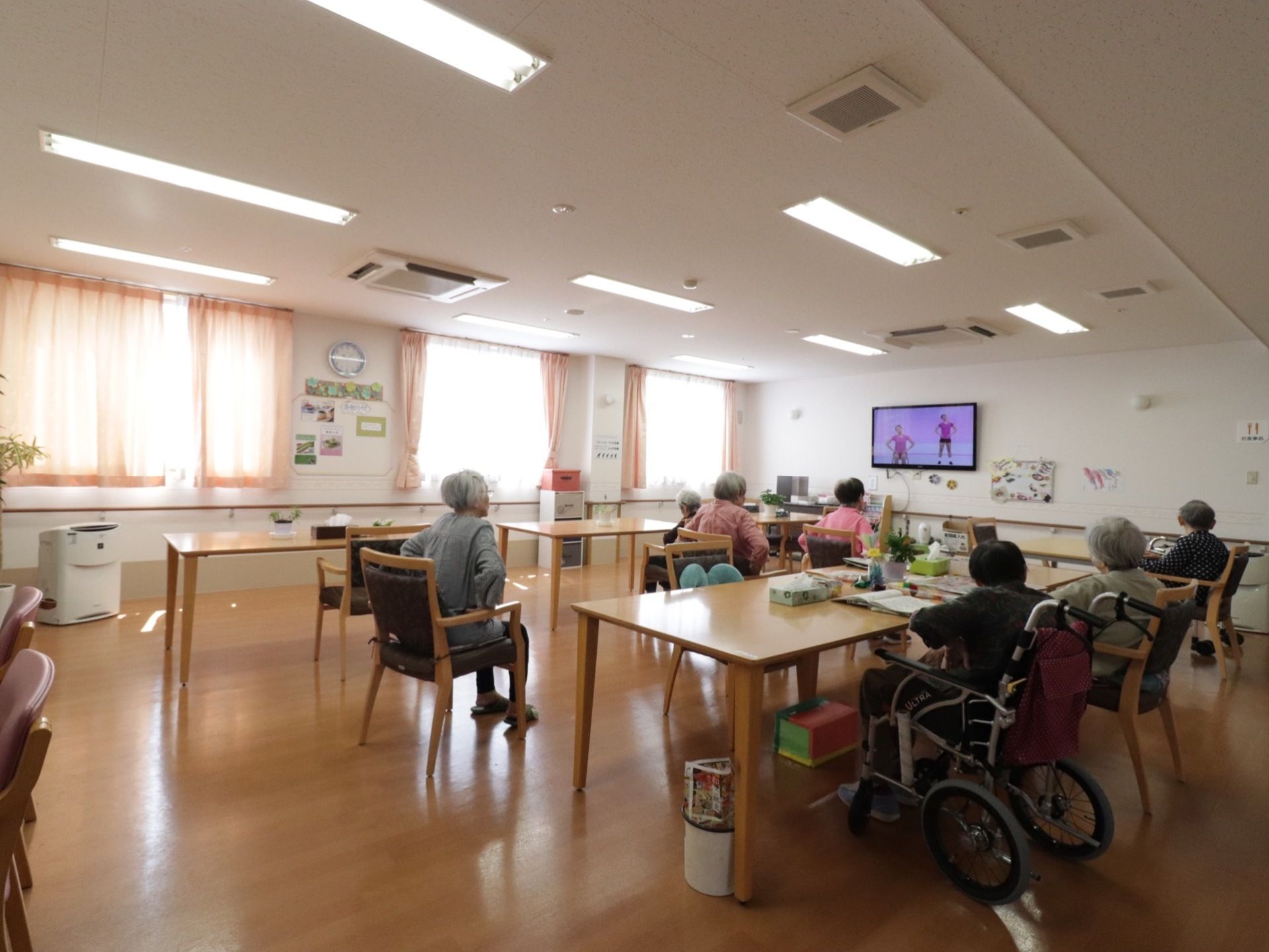 壁面いっぱいに大きな窓がある広い談話室は、テーブルの間隔も広く、座ったまま簡単な体操をすることもできる。
