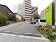 道路から入ってすぐの所に駐車スペースを設け、その奥に10階建ての建物がある。道路から目に留まる位置に看板を掲げている。