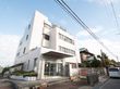 屋上に緑のある、タイル張りの建物である。玄関前に自動販売機や植木鉢が置かれており、スロープが設置されている。