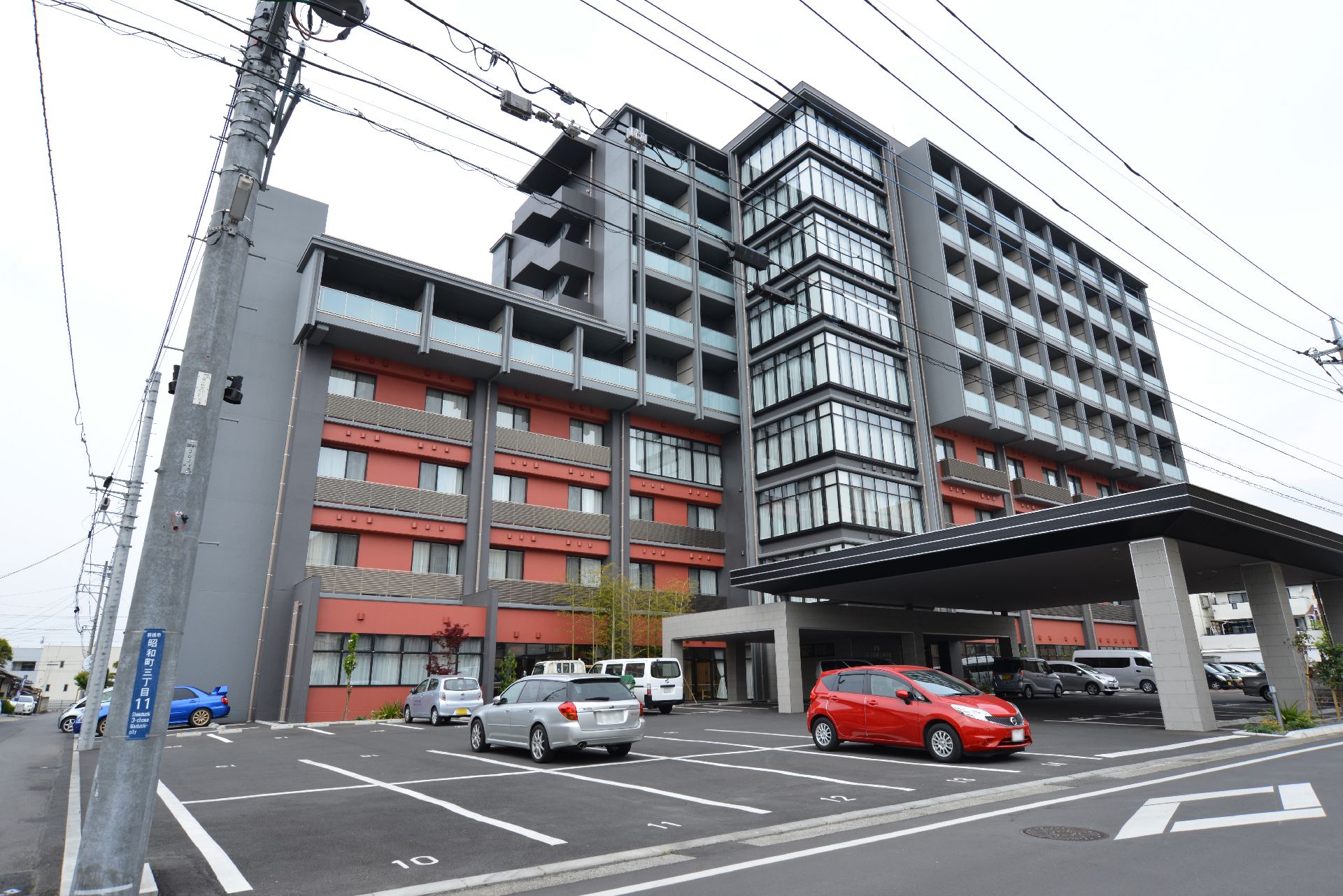 グレーと赤茶色のデザインの外観は、施設ではなく高級なマンションにも見える。建物の前には、様々な草木が植えられている。