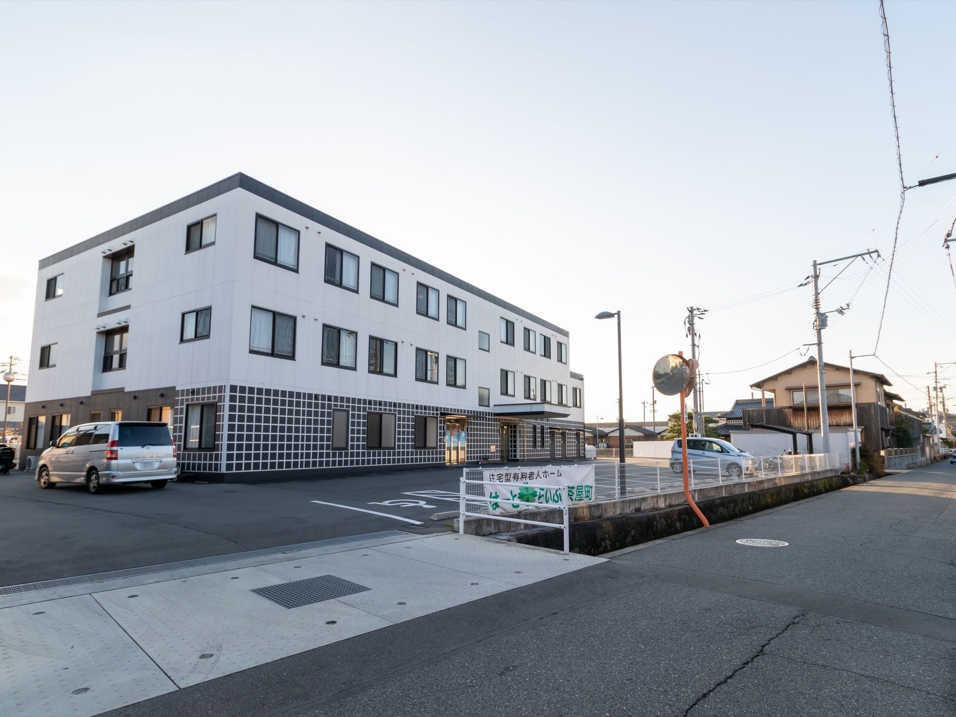 道路沿いに敷地が広がっており、３階建ての施設が建っている。周囲にフェンスが廻らされており、施設名称の書かれた横断幕が取り付けてある。