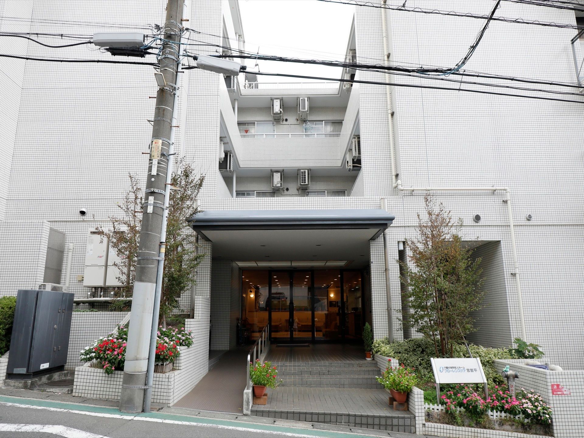 白色を基調とした３階建ての施設である。道路に面して建っており、道路からすぐに階段やスロープが入口に通じている。