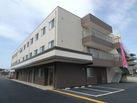 広い敷地内に建てられ、駐車場を完備している３階建ての建物の外観