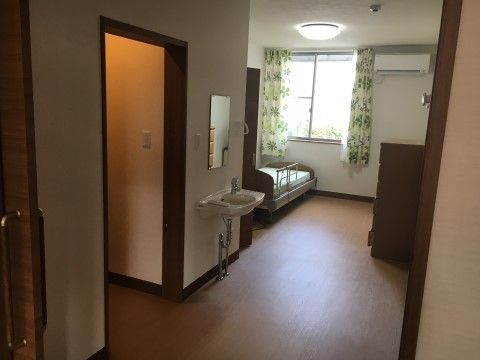 入居者様の居室へはスライド式の扉で出入りすることができる。居室を入ってすぐにトイレが設置してあり、側には洗面台が備え付けられている。