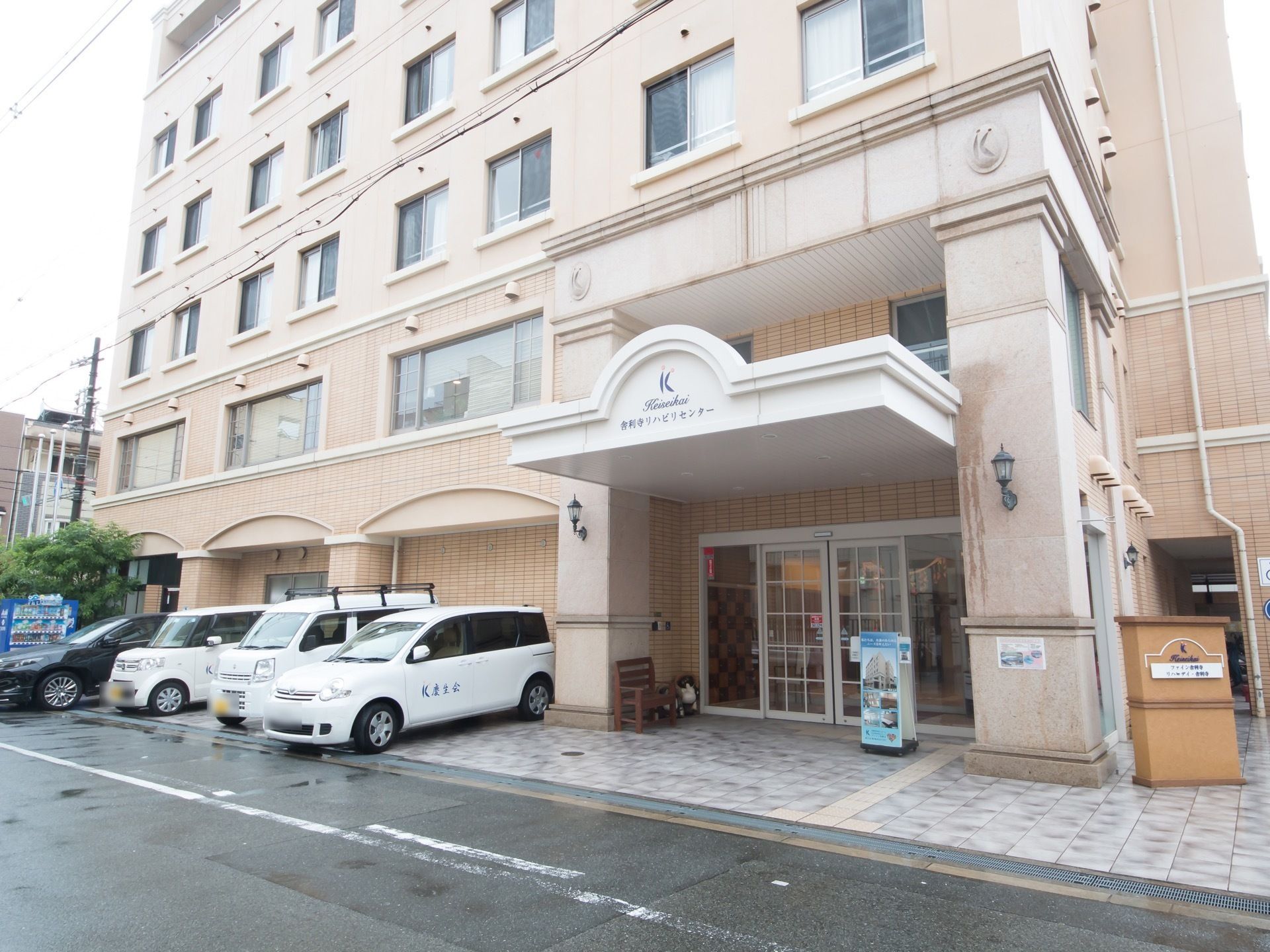 施設は道路に面して立地しており、外壁はベージュを基調としている。入り口は太い柱を採用し、重厚な雰囲気になっている。