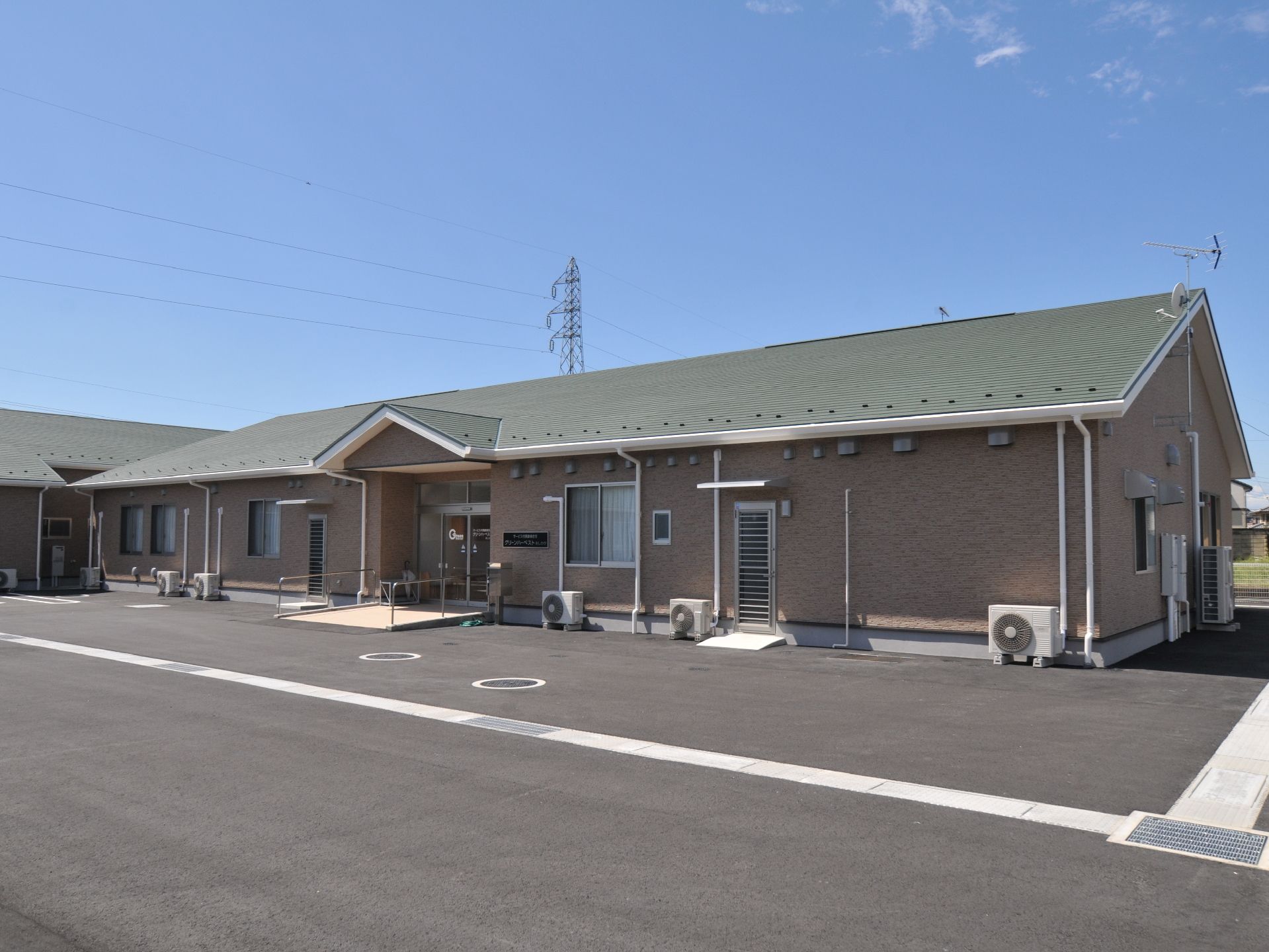 茶色の壁と黒い屋根の色合いが落ち着いた雰囲気のモダンな建物になっています。玄関にはスロープを備え、車いすの方も安心して利用が出来ます。