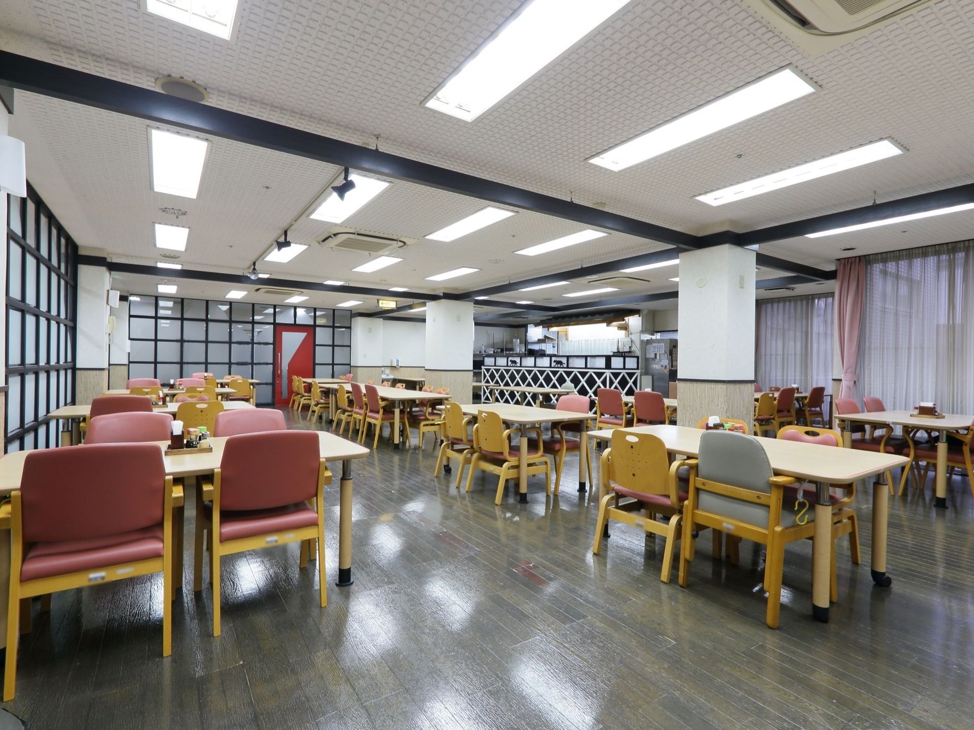 天井には数多くの照明器具が取り付けられており、広いレストラン全体を明るく照らしている。右端には、大きな窓がある。