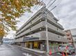 施設の外観が写っており、５階建ての建物となっている。地上部分には柵を境として駐車場があり、車が停められている。