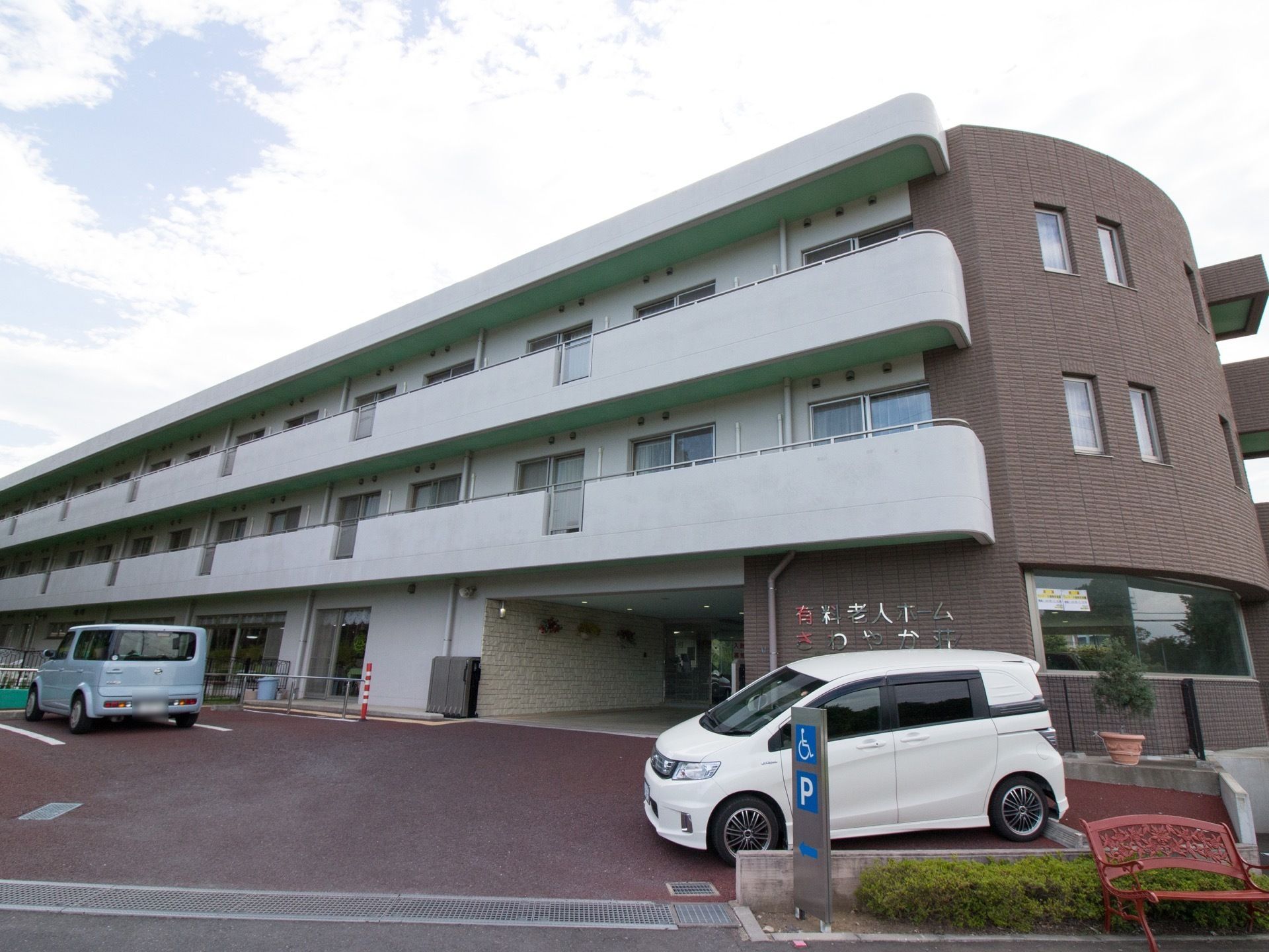 大きな３階建ての施設になっている。白と落ち着いたブラウンの壁になっており、広い駐車場も設置されている。