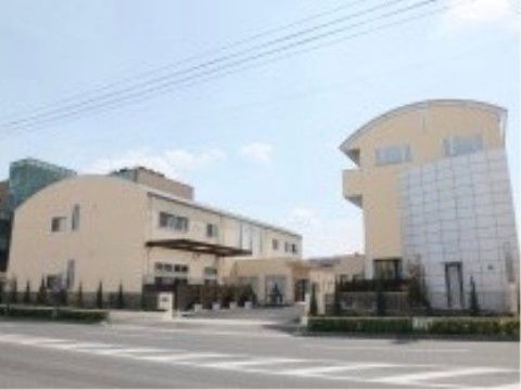 クリーム色でかまぼこ型をした建物の正面外観である。右側は３階建て、左側は２階建てで１階の渡り廊下でつながっている。
