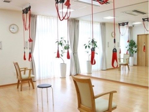 壁の一面が鏡になっており、鏡に向かって椅子が３脚置かれている。リハビリ用のレッドコートが、天井に設置されている。