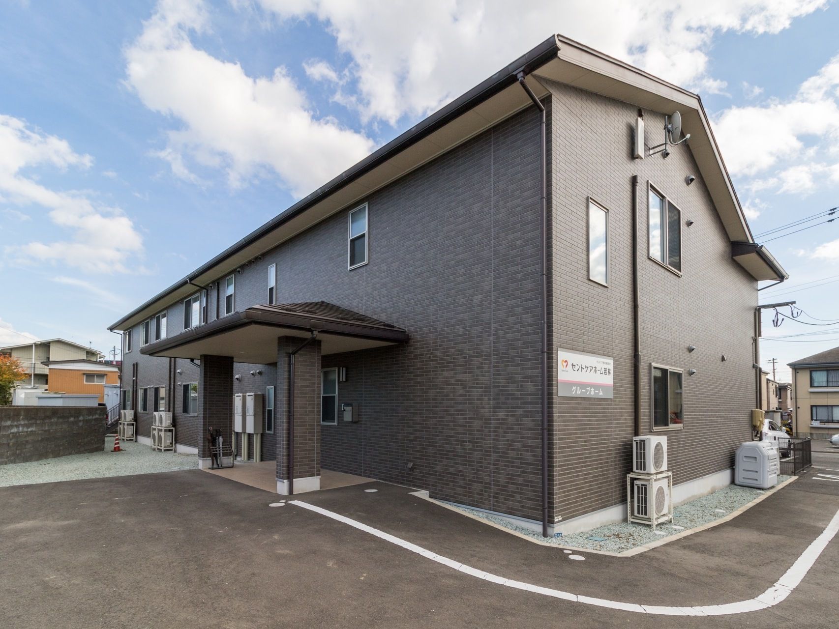 ２階建てで、壁には施設名が書かれた看板が設置されている。玄関部分には屋根がついていて、雨の日の出入りに便利である。