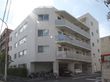 道路に隣接した灰色の外観で４階建ての建物