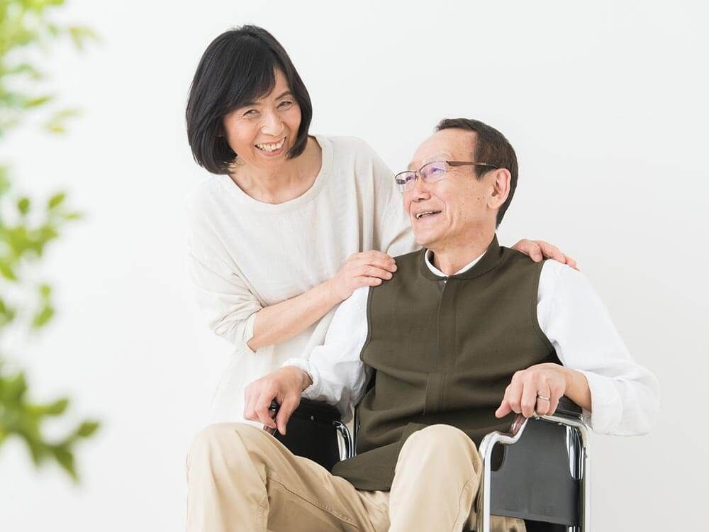 車椅子に乗った高齢男性と介助をする女性