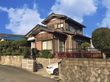 施設は大きな和民家風の外観となっており、1台車が止まっている。敷地内には手入れのされたサツキがたくさん植えられている。