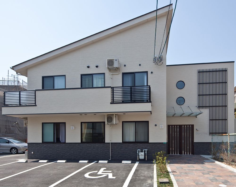 2階建てのアットホームな雰囲気の建物。玄関の近くには緑も植えられている。