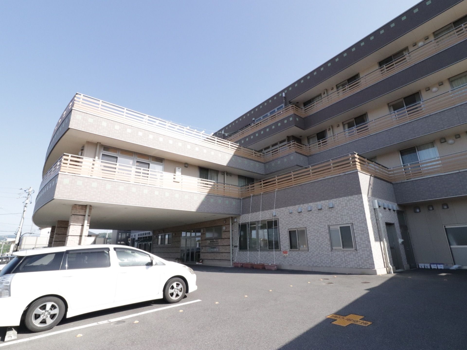 シックな配色の外壁が落ち着いた雰囲気の外観。建て物は4階建てになっており、入り口には屋根や設置されている。