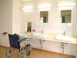 器具を使ってリハビリをする高齢女性と指導をする理学療法士の男性