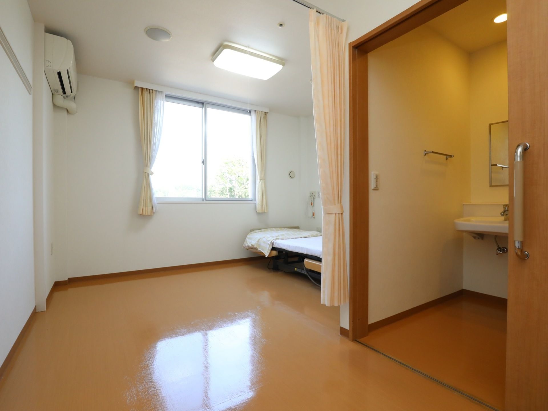 壁は白色で床はフローリングになっている。居室内にあるトイレのドアはスライド式になっており、開いた状態になっている。