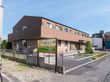 アスファルトに隣接した2階建てでベージュの外観の建物