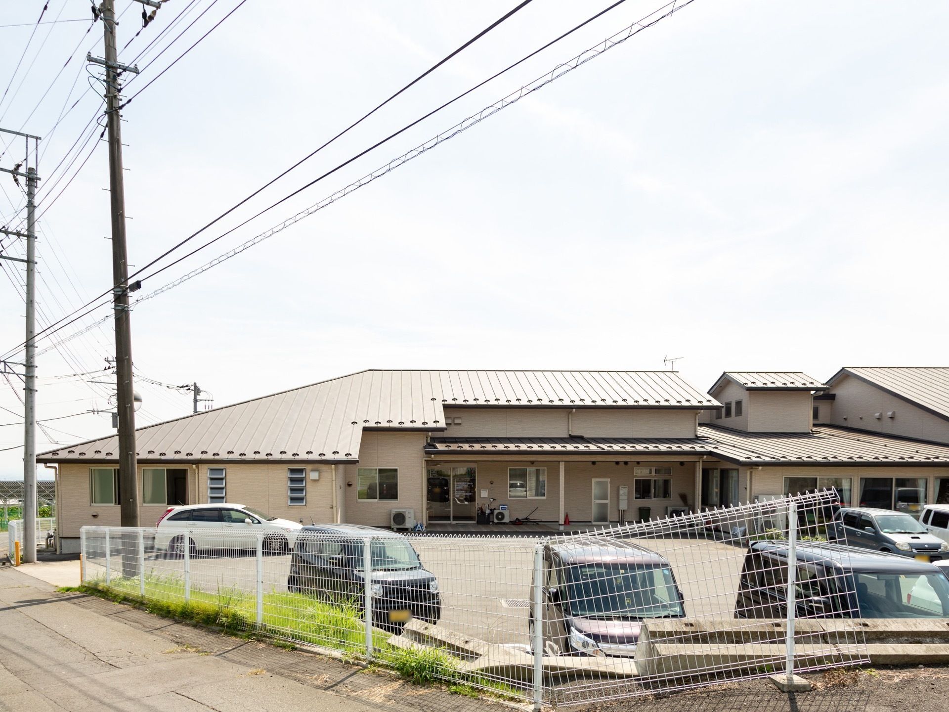 １階のみの平屋建てで敷地前に駐車スペースが広がっている。天井の吹き抜け部分となっている屋根がせり出している。