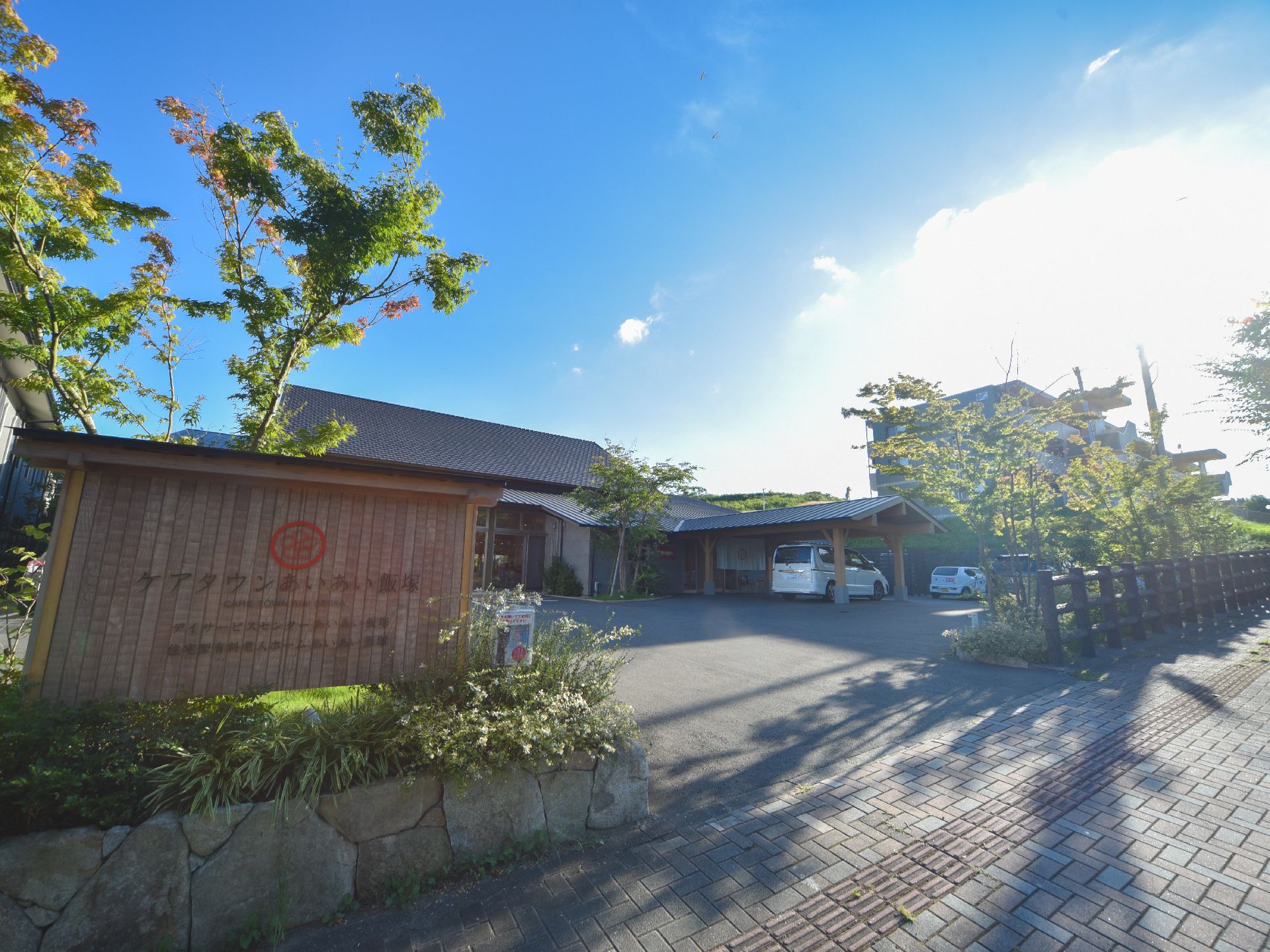 敷地の入り口には施設名が書かれた看板があり、針葉樹が植えられている。また広々とした敷地内には駐車スペースを用意している。