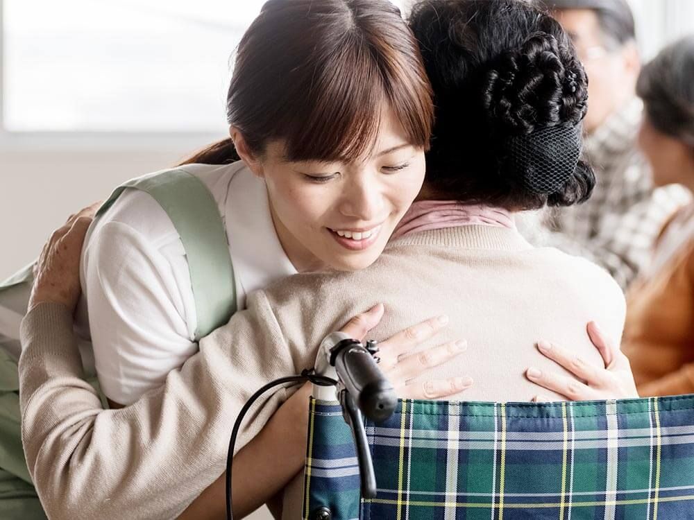 車椅子からの移乗介助をする女性ヘルパー
