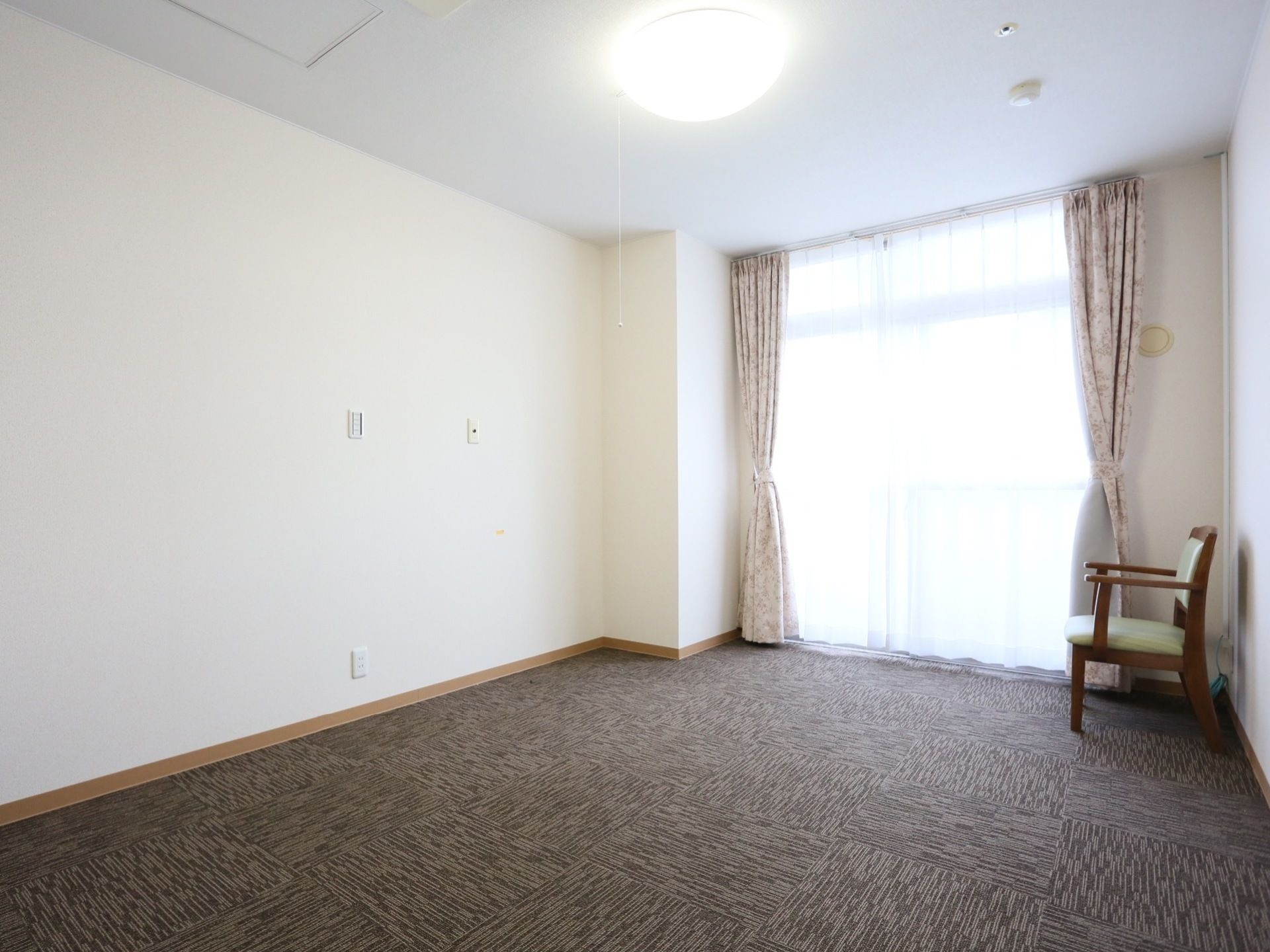 カーペット敷きの柔らかい光が室内に差し込む個室タイプ。入居時に入居者様の生活に合わせたレイアウトになる。