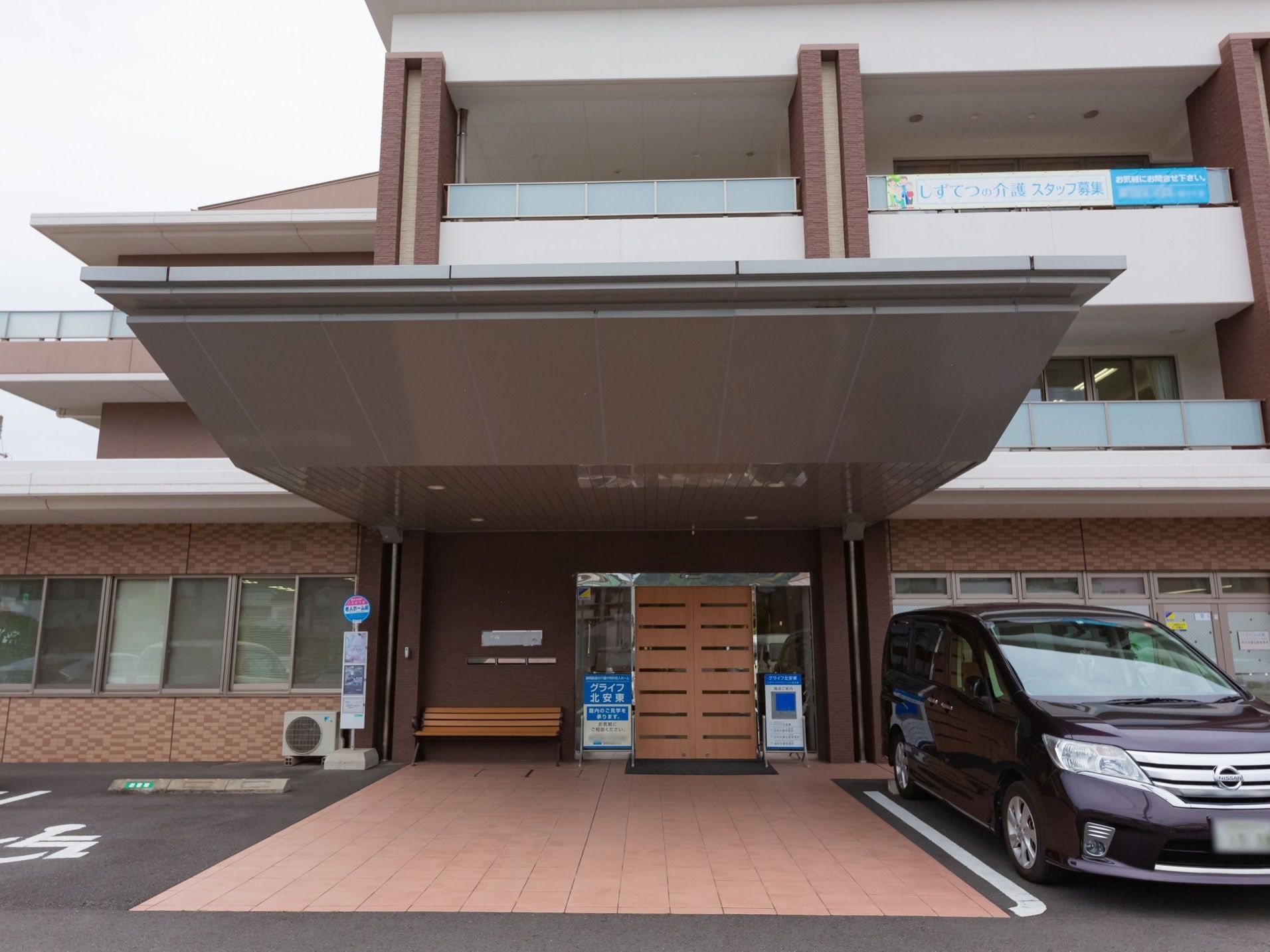 玄関には奥行きのある大きなひさしがある。ひさしのすぐ横に駐車スペースがある。玄関が路線バスの停留所になっている。