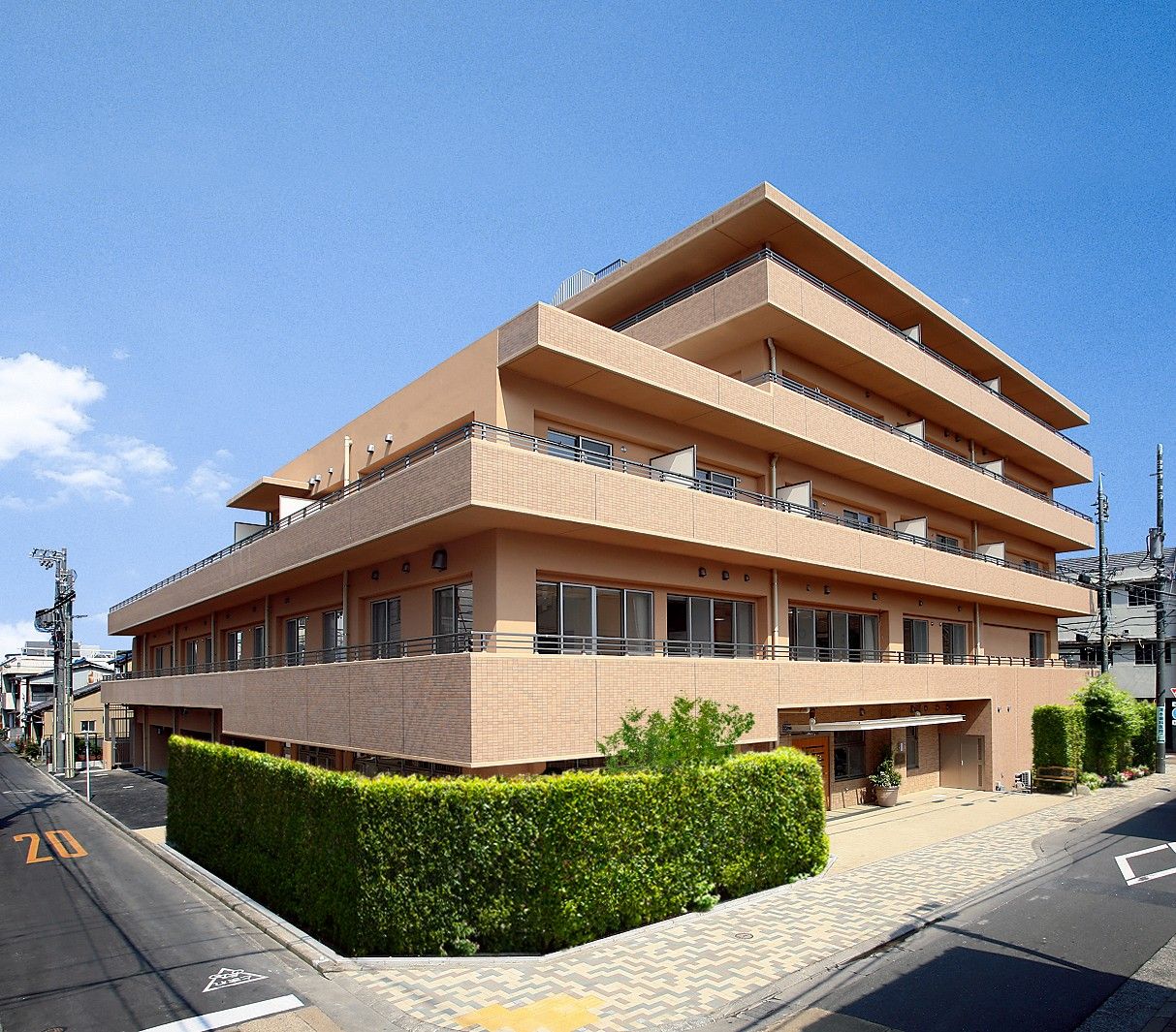 ２面が道路に接している敷地に建っている４階建ての施設である。玄関の左右には背の高い植栽があり、角に施設の看板が設置されている。