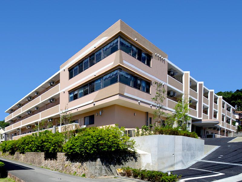 ハイセンスな３階建ての施設である。居室にはベランダが完備されている。建物の前には駐車スペースや手入れの行き届いた植え込みがある。