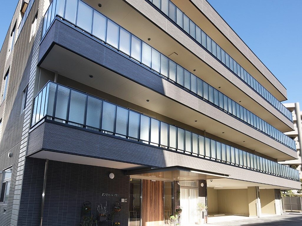 自動ドアのエントランスが見え、ブラウンを基調とした建物の全体像