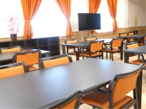 カーテンと椅子の背もたれはオレンジ色になっており統一感がある。窓際の収納庫には入居者様の荷物を収納することができる。