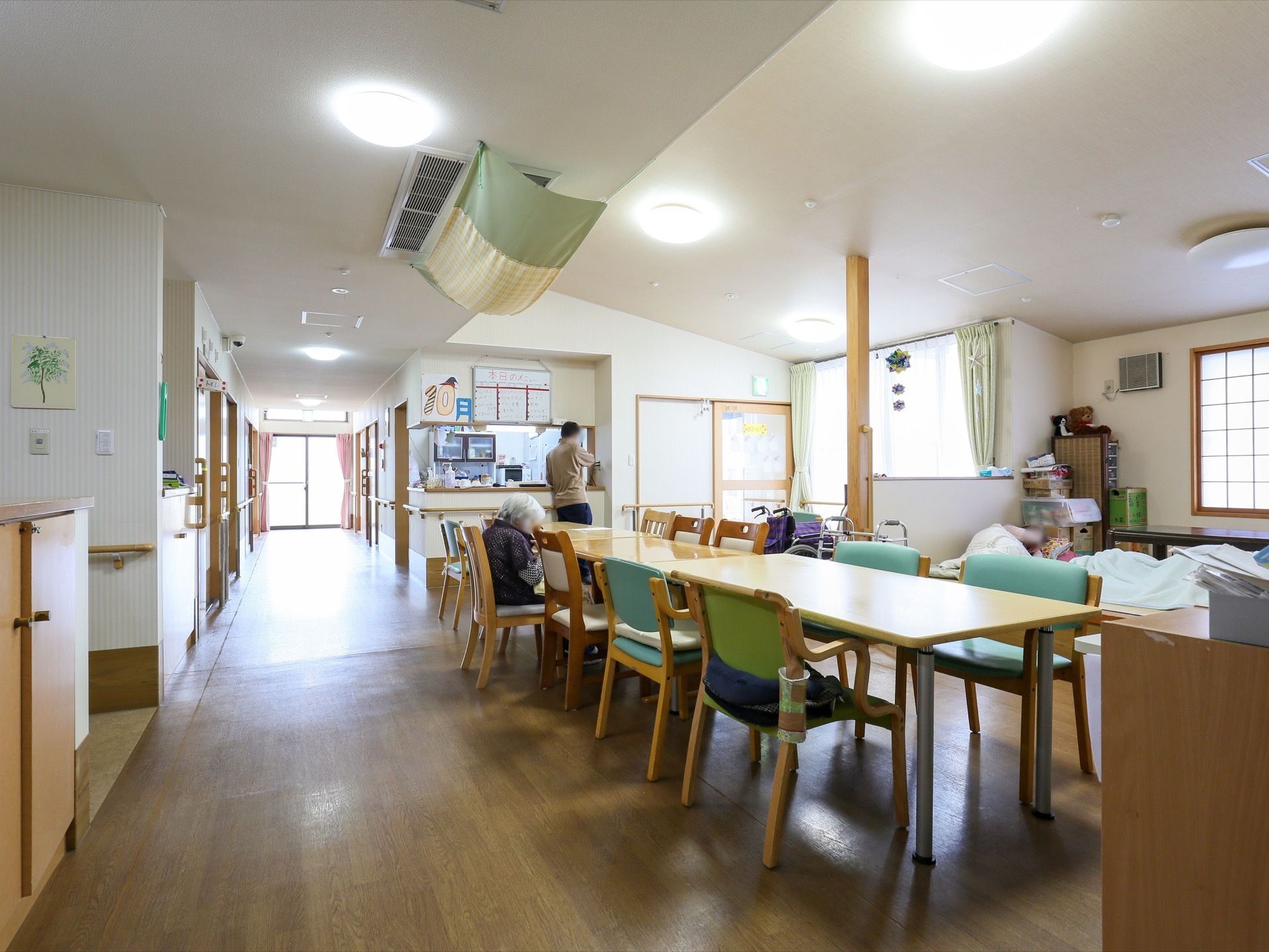 天井が屋根の形に開いた共有スペースである。左奥に向かって廊下が伸びており、突き当りにある窓から光が差し込んでいる。