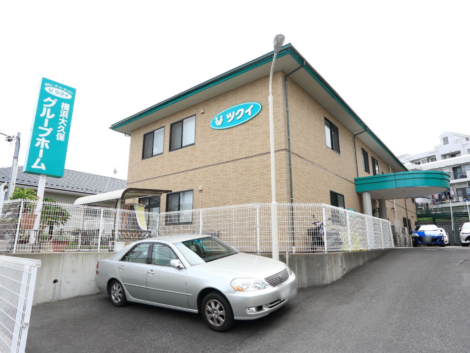 2階建施設の1階には、庭に面して屋根がついている洗濯物干し場が設置されている。建物の横と前に駐車場が設けられている。