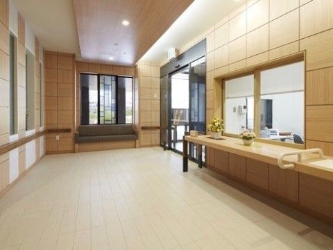広々としたエントランススペースには、大きな窓の受付がある。カウンター台には花の鉢を飾っている。出入口ドアの横側にソファを備えている。