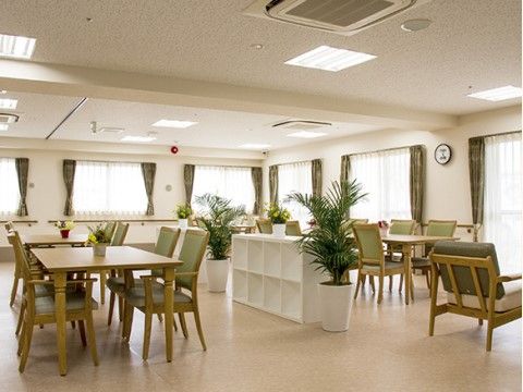 壁面に窓が多くあり、自然光が良く入り広々とした空間に、ダイニングテーブルと椅子のセットが設置してある。中央に荷物置きの棚がある。