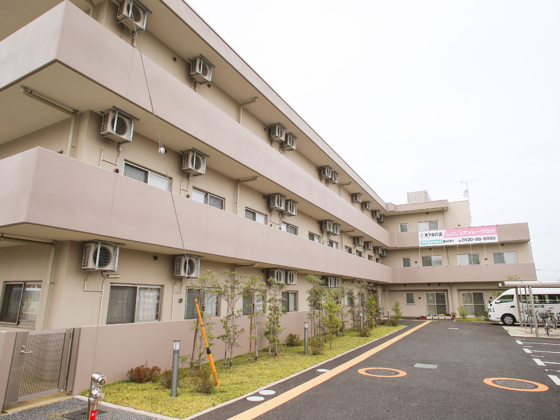 3階建の建物で、駐車場と駐輪場が付いている。駐車場と建物の間には植物が植えられている。消火栓が設置されている。