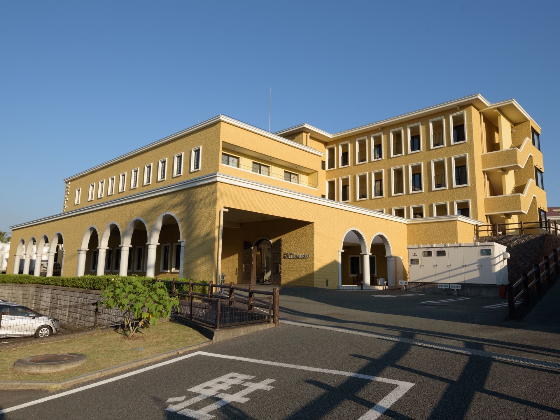 施設は、４階建てでホテルのような佇まいである。玄関ポーチには車で入ることができる。イエロー系の外観に、白い窓枠が映えている。