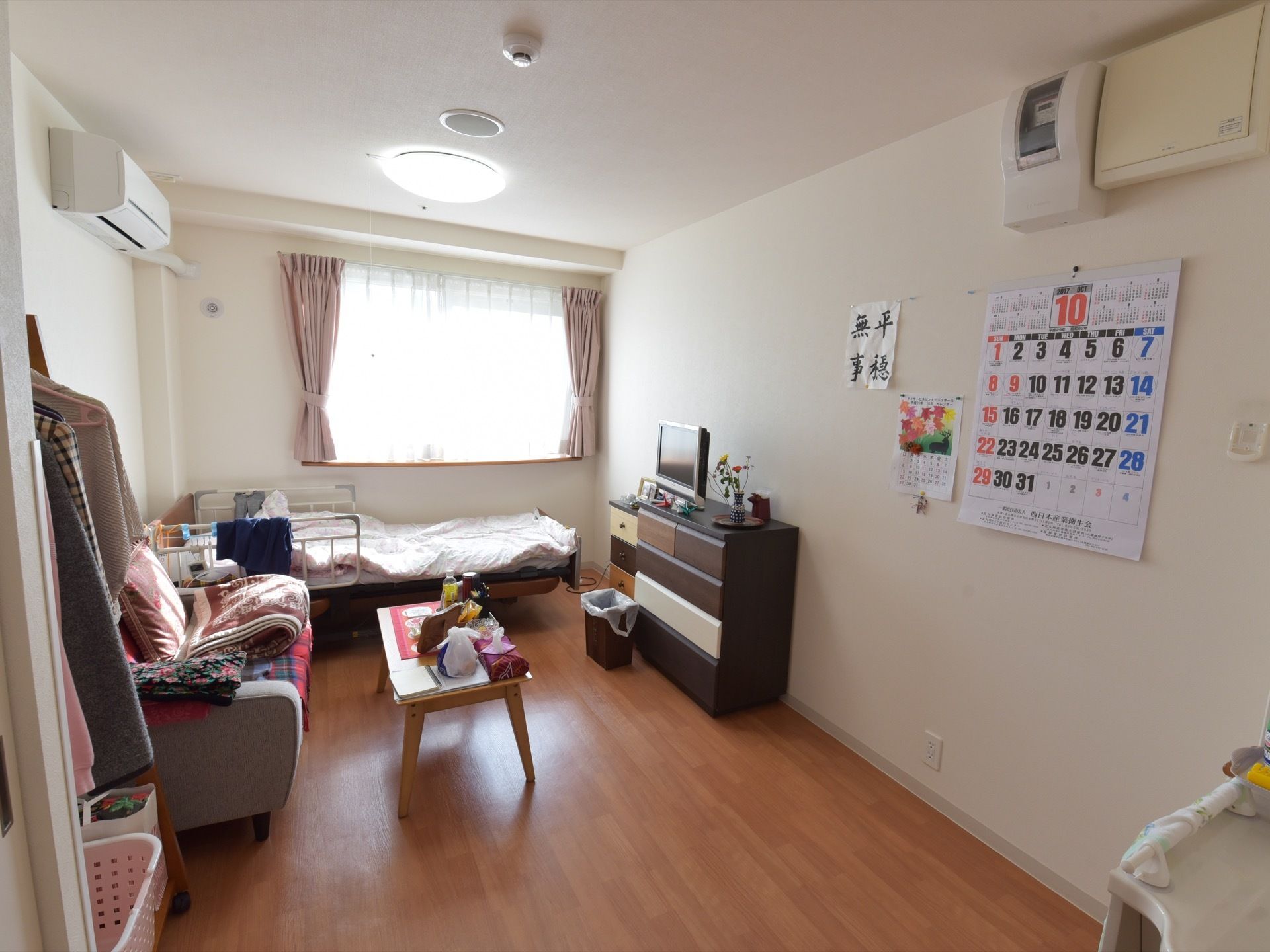 現在、入居者様が実際に生活している部屋の様子である。ベッド、テーブル、椅子、チェスト、テレビが設置されている。