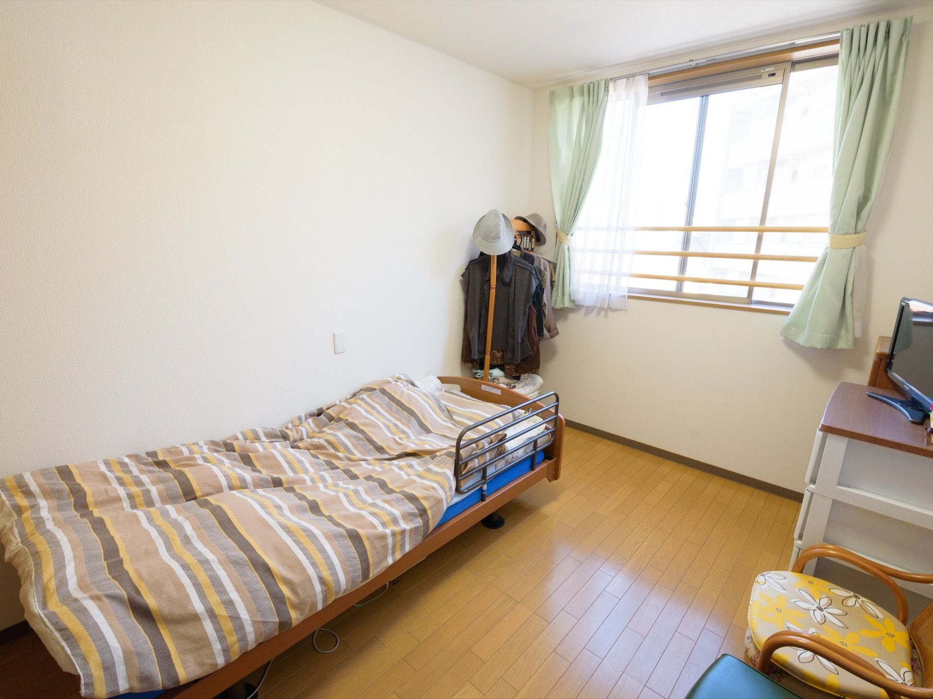 白色の天井と壁に木目の床の内装の居室スペースである。正面には、窓があり、前方に３本の手すりを設置している。