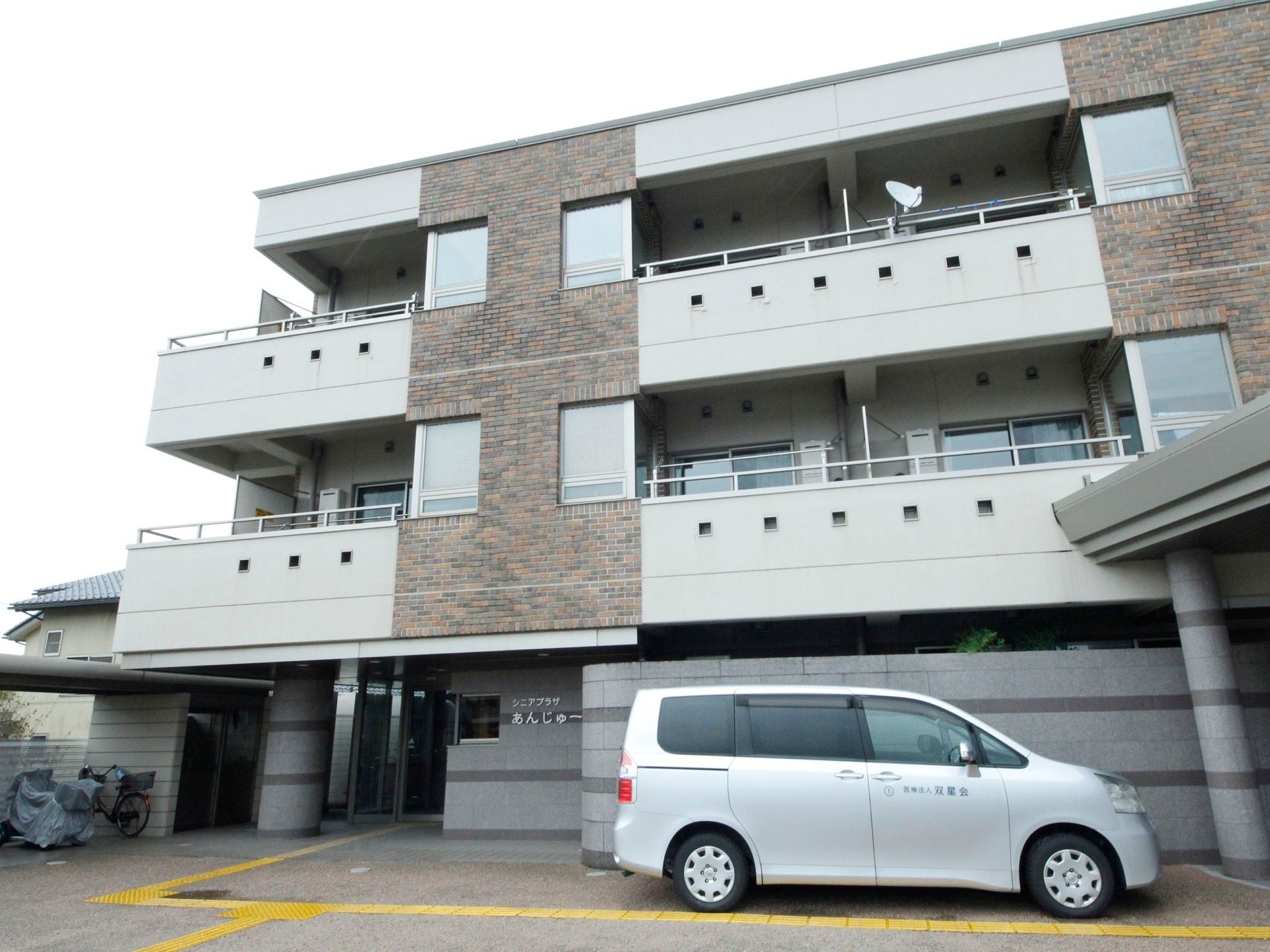 施設は三階建ての建物で、二階以上にはベランダを設置している。前面には駐車スペースを設け、専用車をとめている。